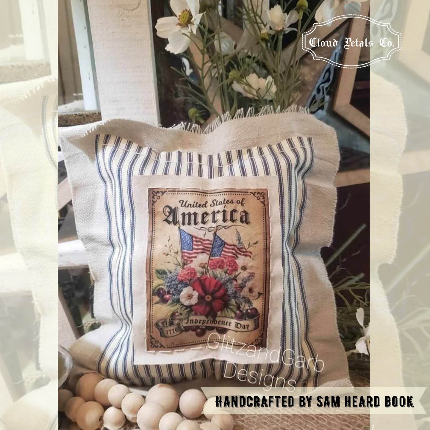 Decorative pillow with 'United States of America' design and floral elements, placed on a surface with a blurred background.