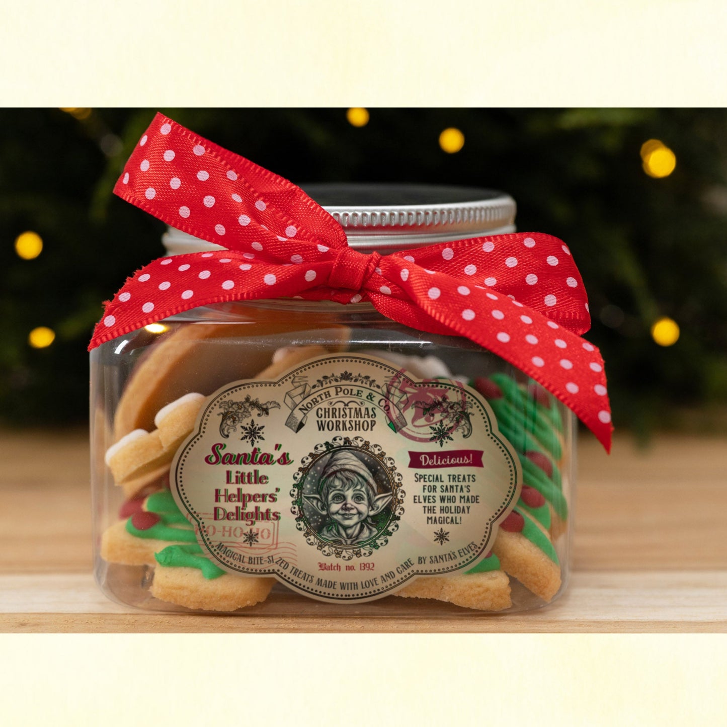 Jar with vintage-style Christmas label and red polka dot ribbon on a wooden surface with blurred lights in the background.