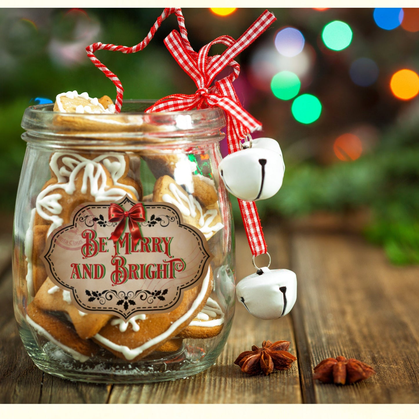 Decorative jar with Christmas-themed label and festive decorations on a wooden surface with blurred lights in the background.