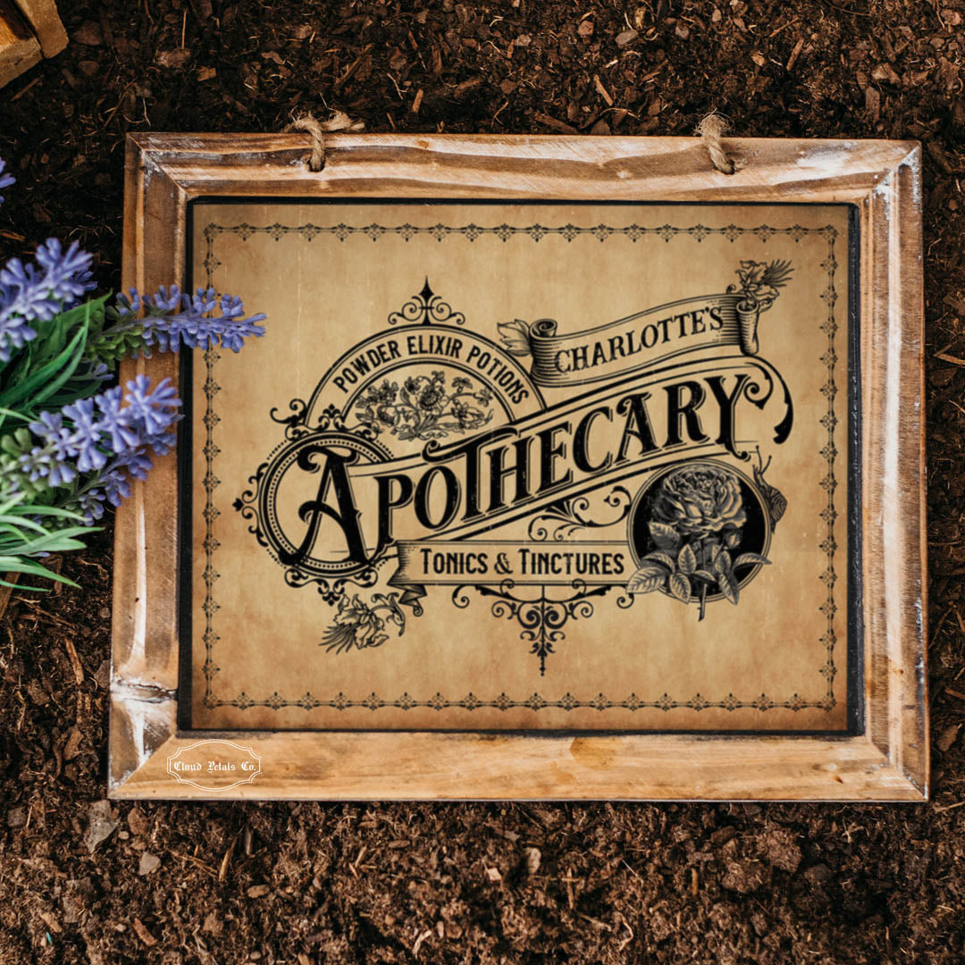 Wooden sign with 'Charlotte's Apothecary' design on a dark, textured background with lavender flowers.