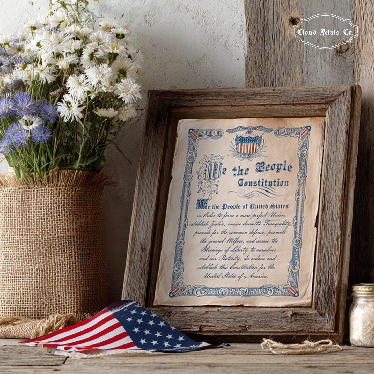 Framed copy of the Constitution with flowers and an American flag on a wooden surface.
