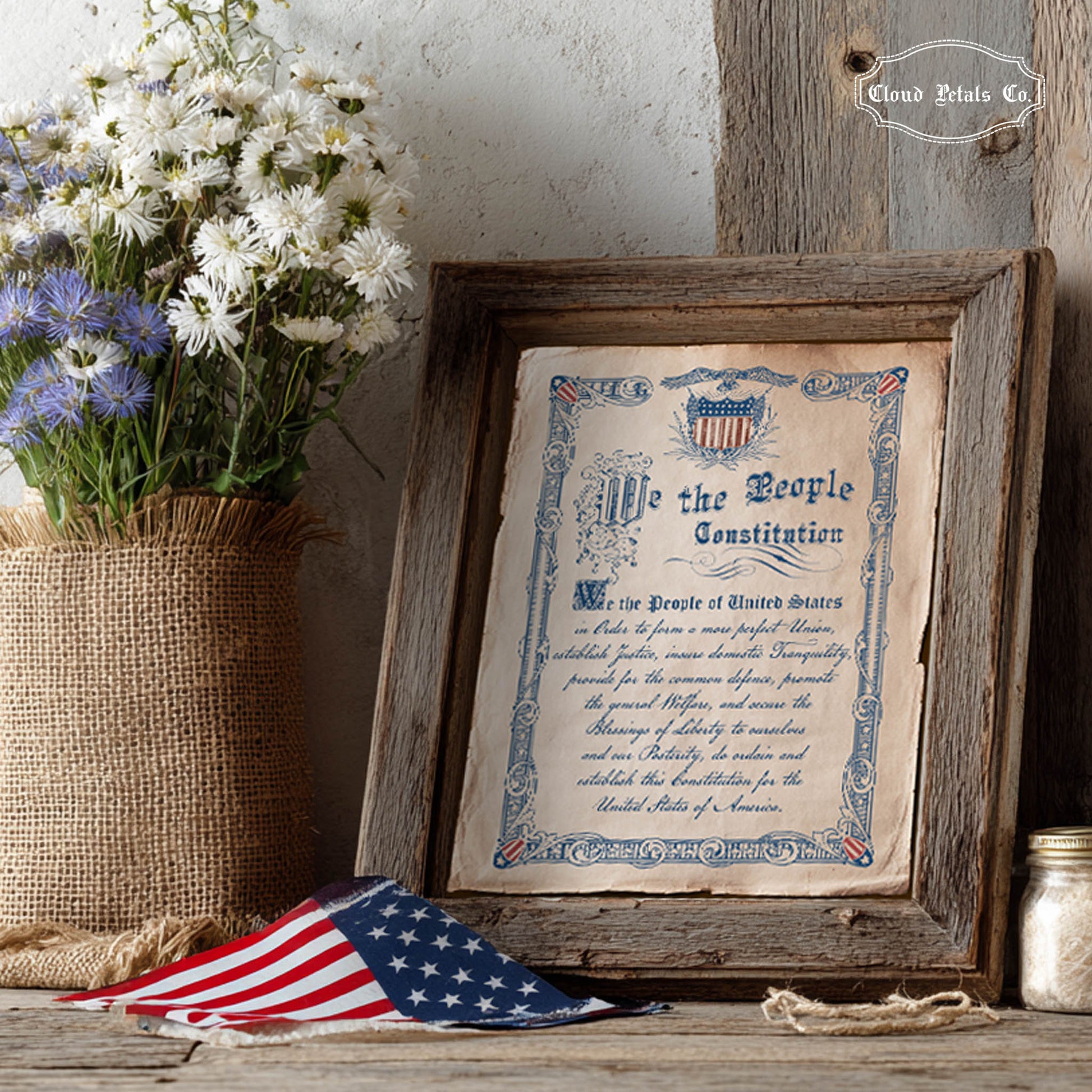 Framed copy of the Constitution with flowers and an American flag on a wooden surface.