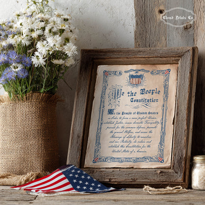 Framed copy of the Constitution with flowers and an American flag on a wooden surface.