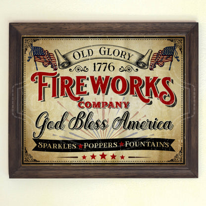 A vintage style 4th of July fireworks sign with the text 'Old Glory 1776 FIREWORKS COMPANY God Bless America' and American flags, sparkles, and fountains mentioned below. The sign is presented in a wooden frame.