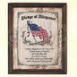 A vintage style wall art featuring the Pledge of Allegiance to the flag of the United States of America, with a flag depicted in the background. The art is bordered with a floral pattern and has a rustic wooden frame.